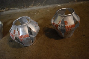 two exploded CM Instantaneous Blast OC Grenade cans from defense technology orange writing on split silver cans. The lids have been completely blown off and the canisters have split along 6 different seems in pre-machined grooves.